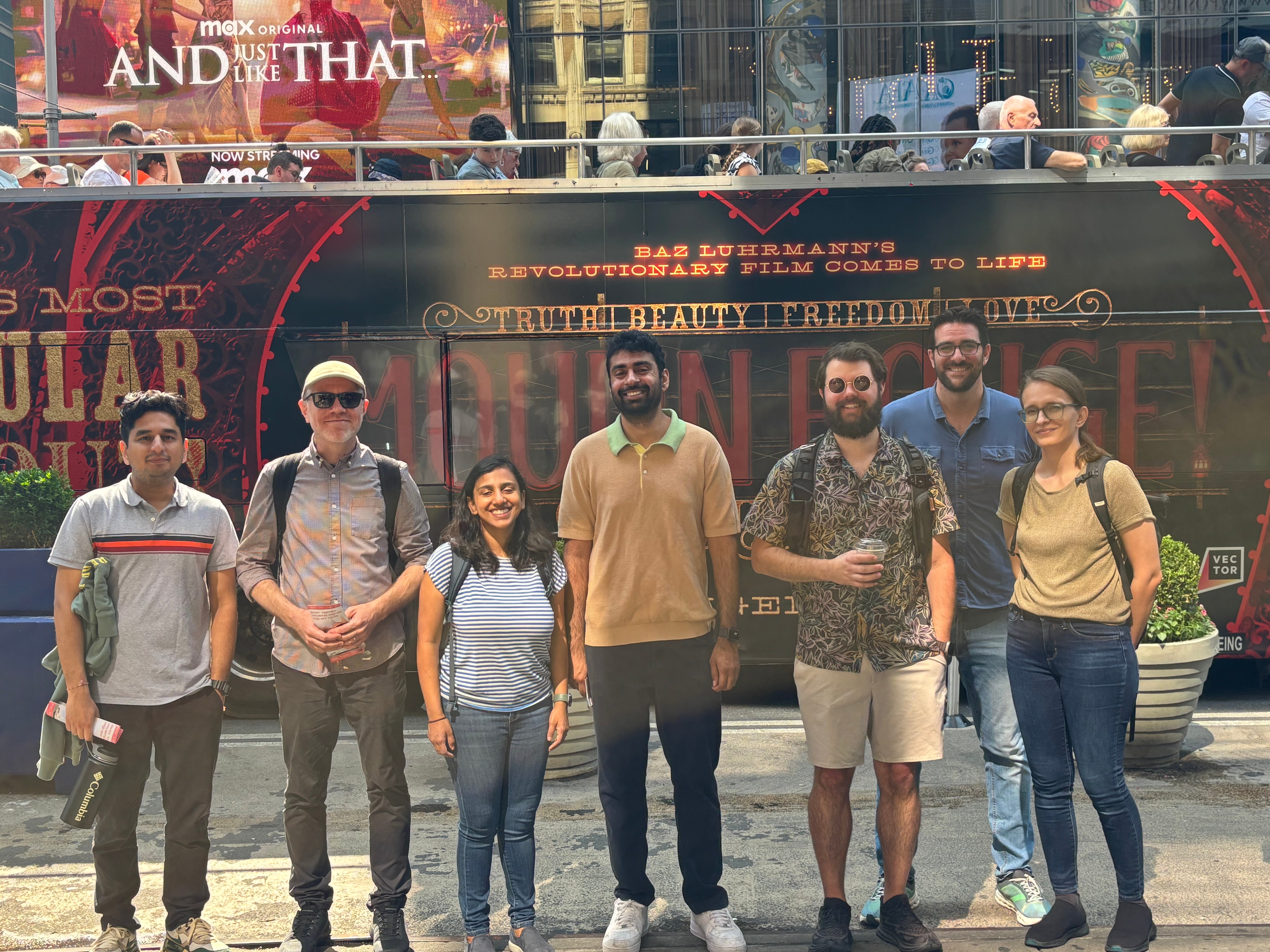 The Atomic team posing together in front of a tour bus in New York City